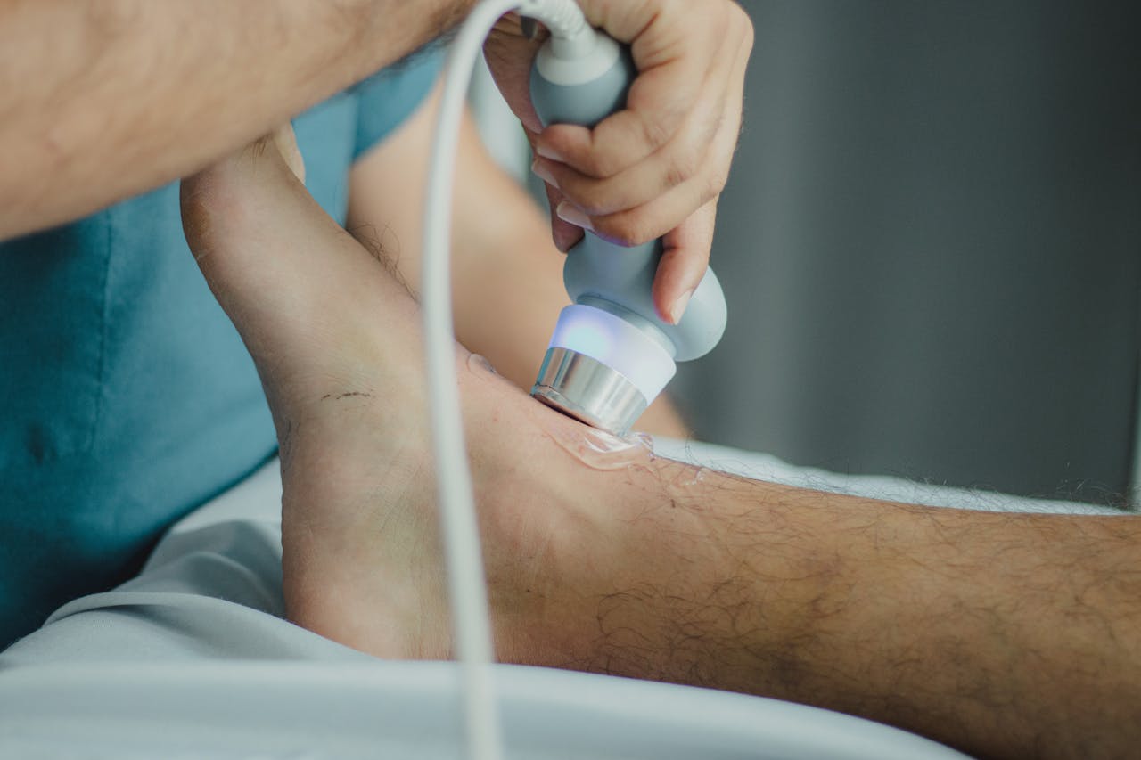 about-us Professional physiotherapist using ultrasound device for leg treatment.